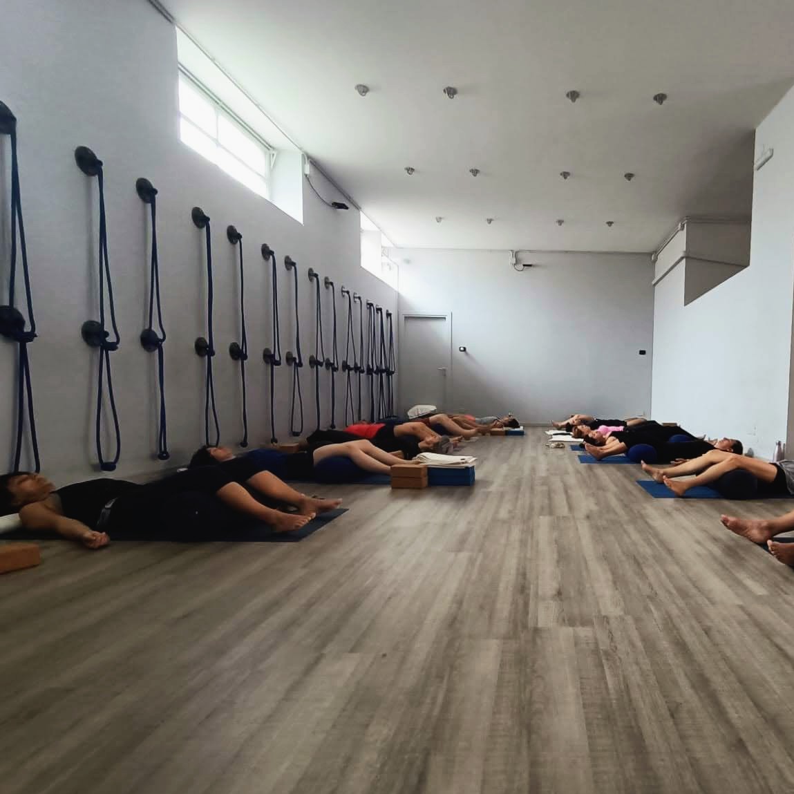 Allievi durante la fase di rilassamento finale Savasana con bolster e mattoncini nella sala corsi di Kalishiva Yoga Torino