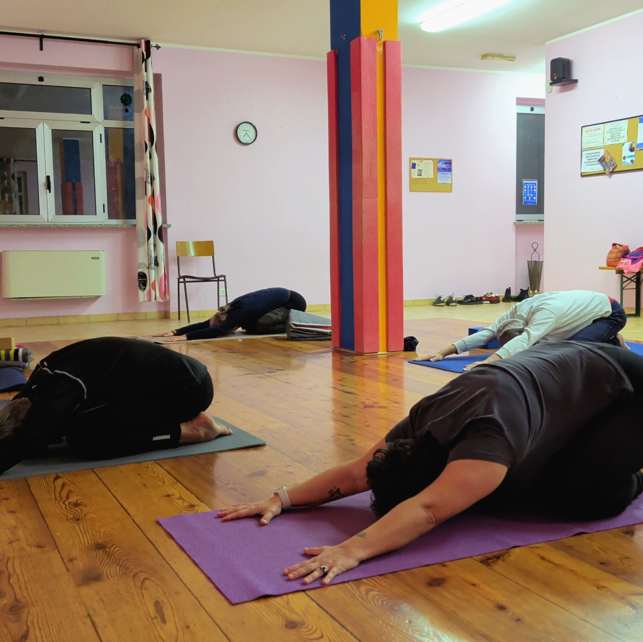 Allievi eseguono la posizione Adho Mukha Virasana su tappetini durante una lezione di yoga di Kalishiva a Villarbasse